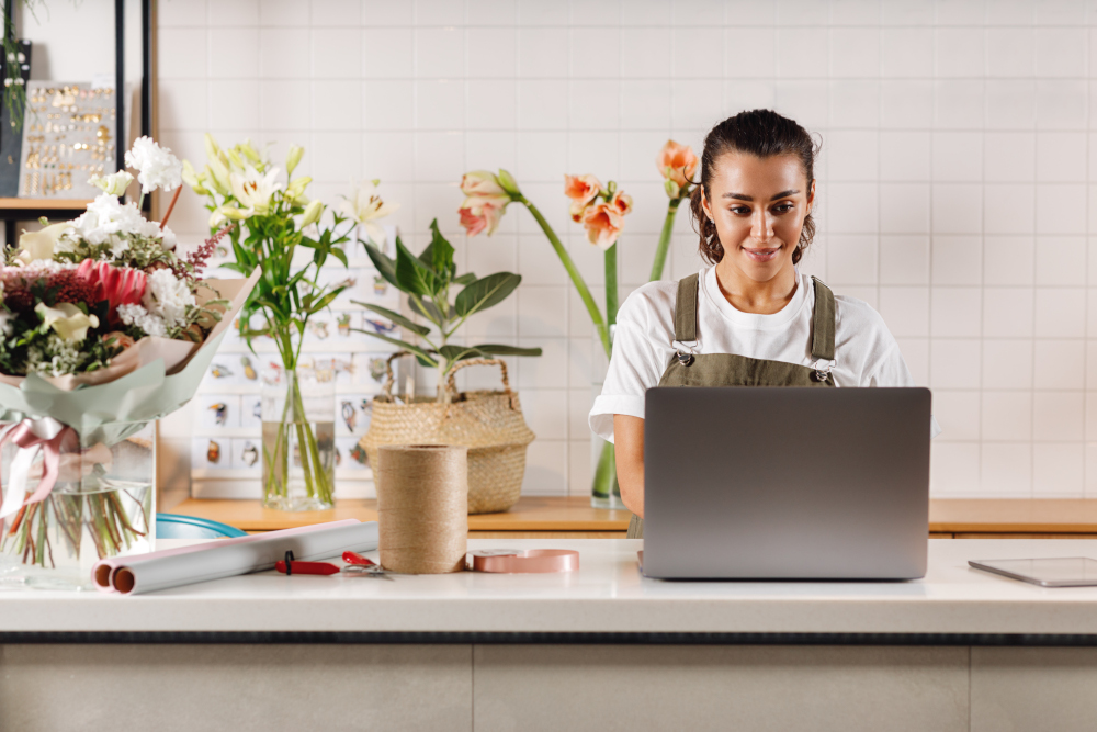 Image young woman florist using laptop